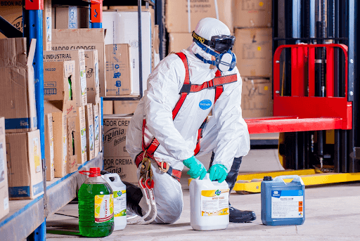 Person wearing a white suit holding a white container of chemical