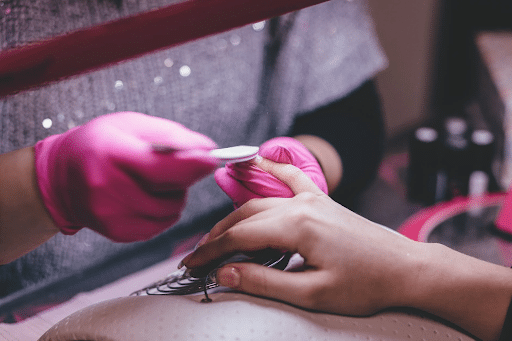 pink gloves giving a manicure to a lady’s hand