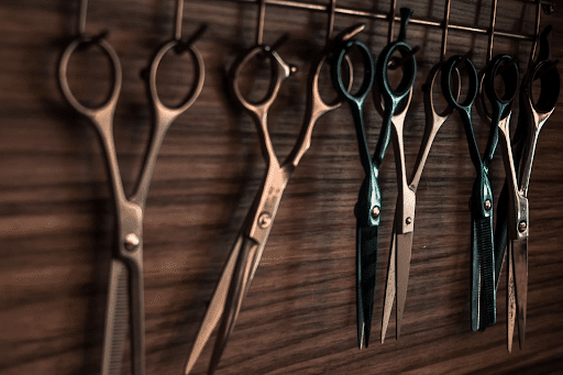 Four grey and 2 blue-green scissors hanged on a scissor holder