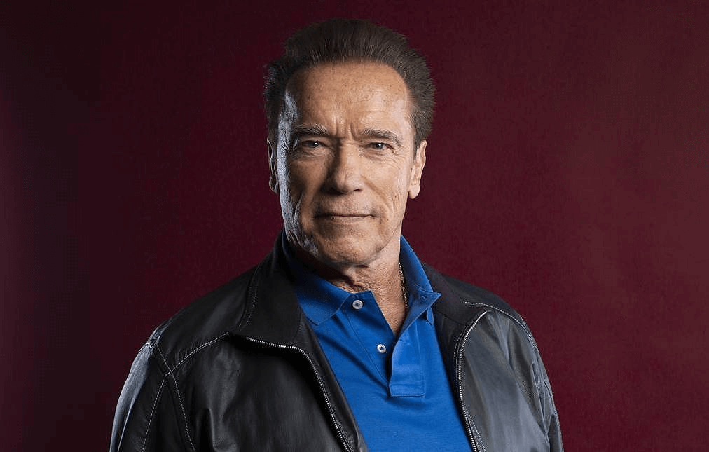 Arnold Schwarzenegger smiling in front of a black background