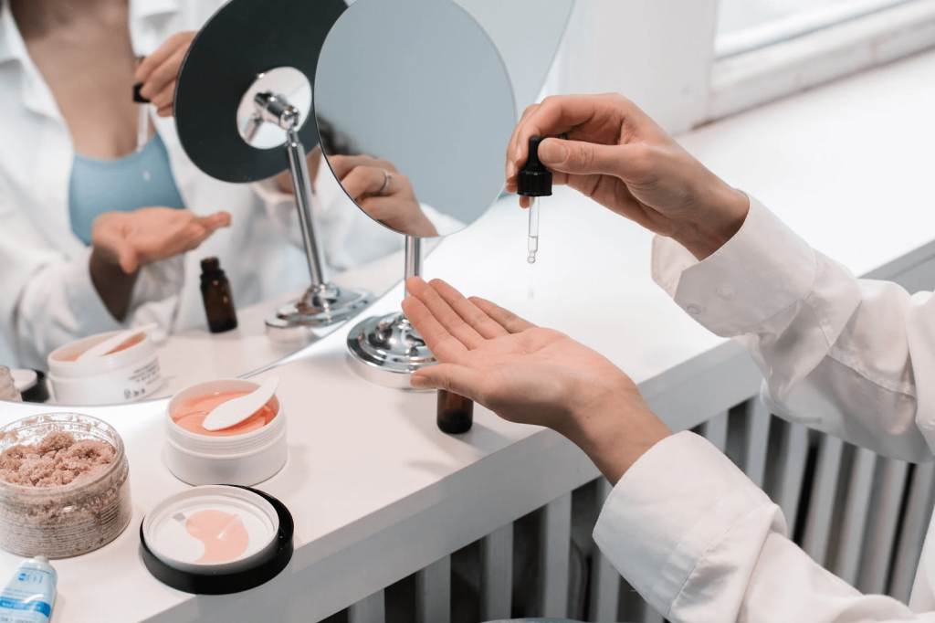 person’s hand with a beauty dropper, facing a mirror (beauty care image)