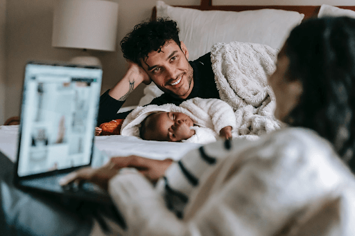 Photo of a multiethnic family with their baby and wife in front of a laptop