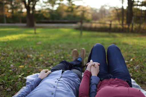 Couple holding hands while lying on the ground