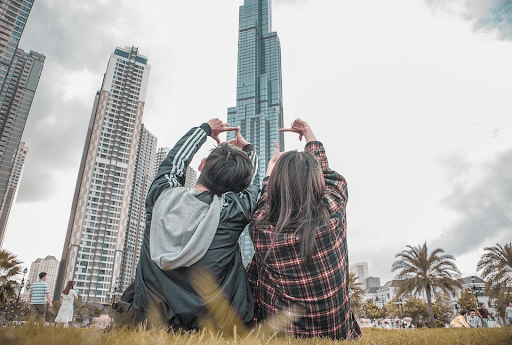 Young couple sitting on a grassy ground with their backs on the camera