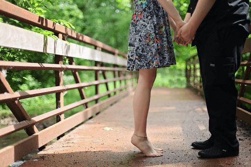 Couple facing each other and standing on a bridge