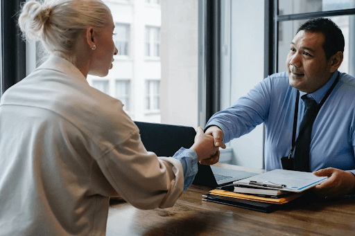 A businessman shaking an applicant’s hand inside his office