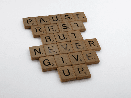 brown wooden blocks spelling out “pause rest but never give up”