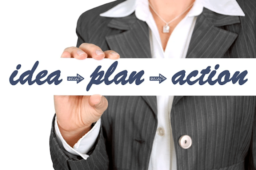 A businesswoman holding a card that says idea ‘plan’, ‘action’