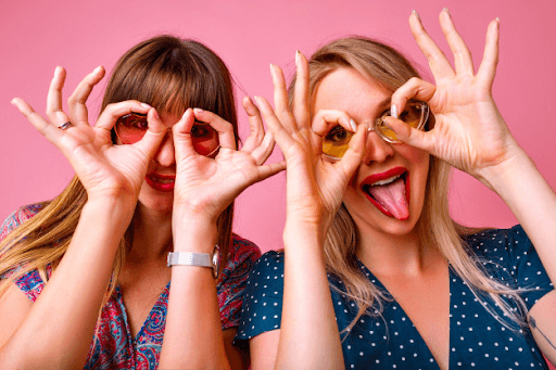 two women imitating glasses with their hands with one girl having her tongue out (crazy friends image)