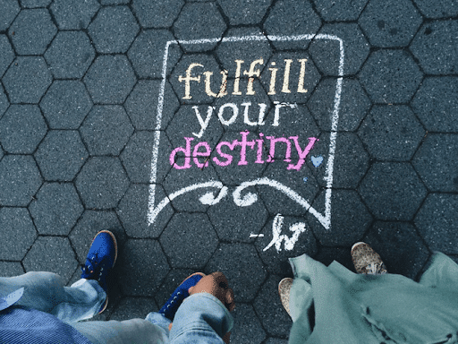 Two people standing near a “fulfill your destiny” street artwork