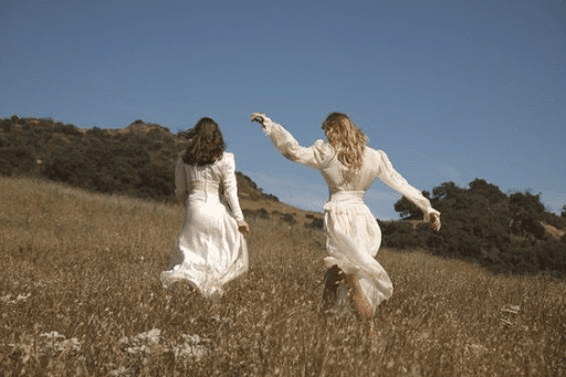 Two women dancing on a grass field