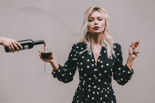 Confident woman standing with wine glass and cigarette