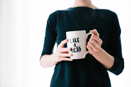 A headless woman holding a white mug with a “LIKE A BOSS” label