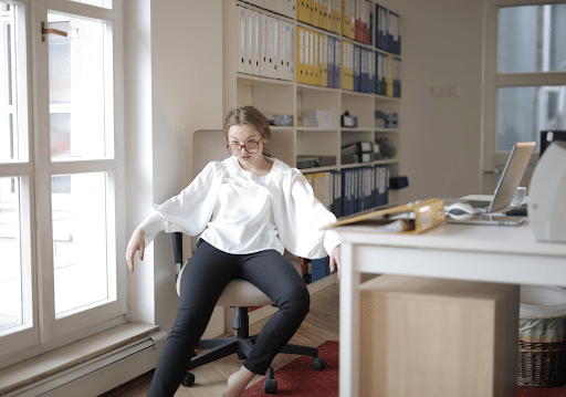 Arrogant woman in a white top and black pants sitting in an office