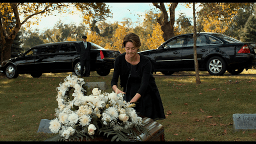 a scene of Hazel putting white flowers on Gus’ casket