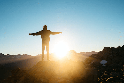 Silhouette of a person standing on a hill during sunrise