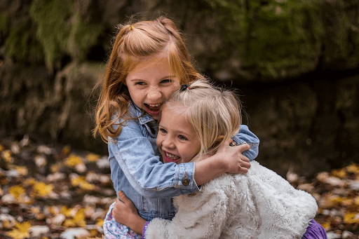  two sisters hugging each other and smiling