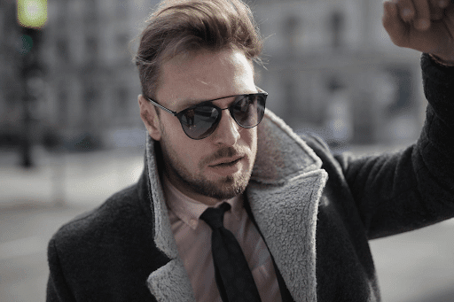 confident and classy man wearing preppy clothes and sunglasses in a city street