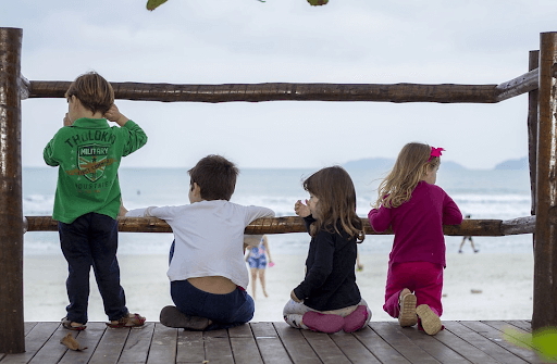 Four kids on a deck near a beach