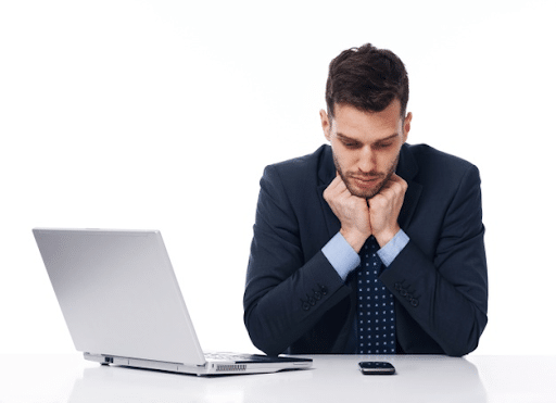 A businessman with his hands on his chin while looking at his phone