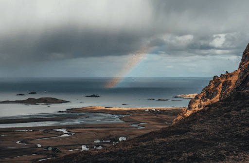 End of a rainbow on an ocean on a cloudy day