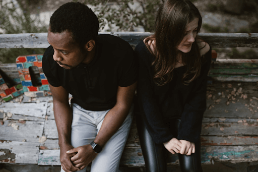  Man and woman sitting on a bench while clutching their own hands