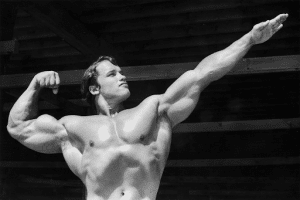 black and white photo of Arnold Schwarzenegger as Mr. Olympia flexing his muscles