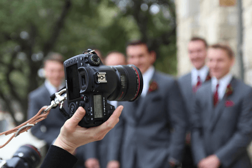 Hand of a man in a black suit wearing a digital camera