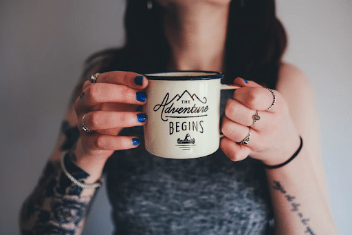 A woman holding a mug with a “The adventure begins” print