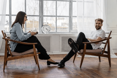 Woman Sitting on Brown Chair talking with a man