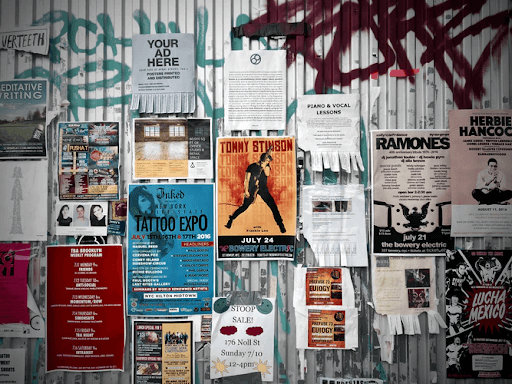 Assorted posters posted on a grey wall