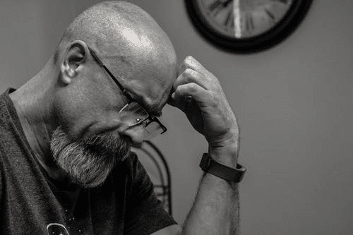 Grayscale Photo of Man Thinking In Front of Analog Clock